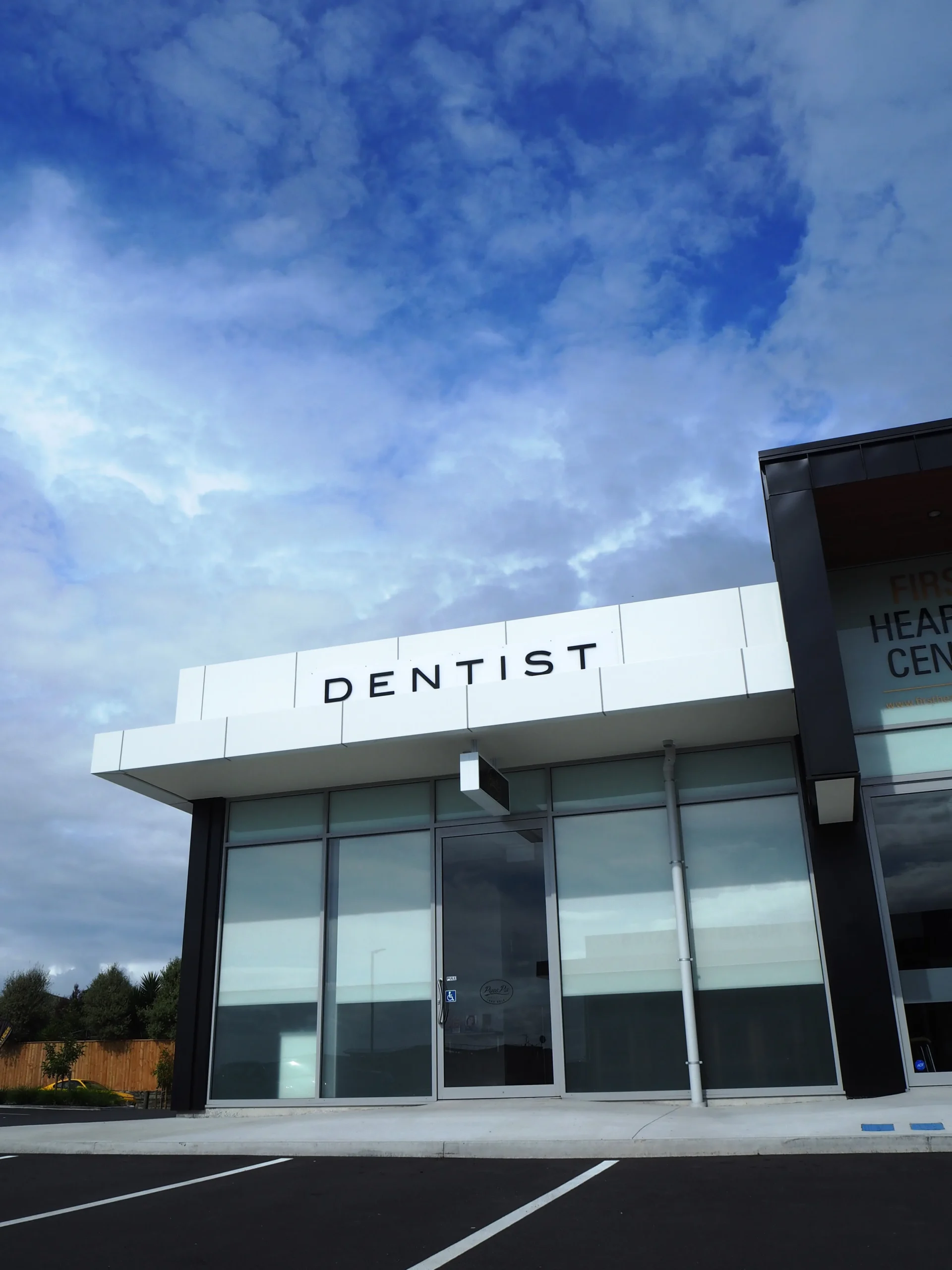 Modern dental office exterior with large windows and blue sky